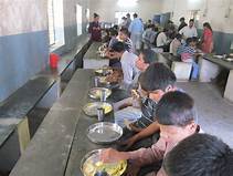 Children being served food along a row in the school dining hall.