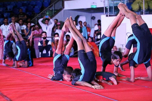 Jnanasindhu students performing an advanced group yoga formation at a competition.
